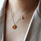 Collier Etincelle en acier doré avec pendentif rond orné d'une étoile et d'un cristal brillant, porté autour du cou. Face visible, verso personnalisable.
