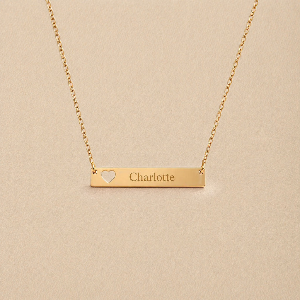 Collier plaque cœur ajouré personnalisable en doré, gravé avec le prénom Charlotte, sur fond beige— Douceur Visée Bijoux