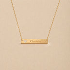 Collier plaque cœur ajouré personnalisable en doré, gravé avec le prénom Charlotte, sur fond beige— Douceur Visée Bijoux