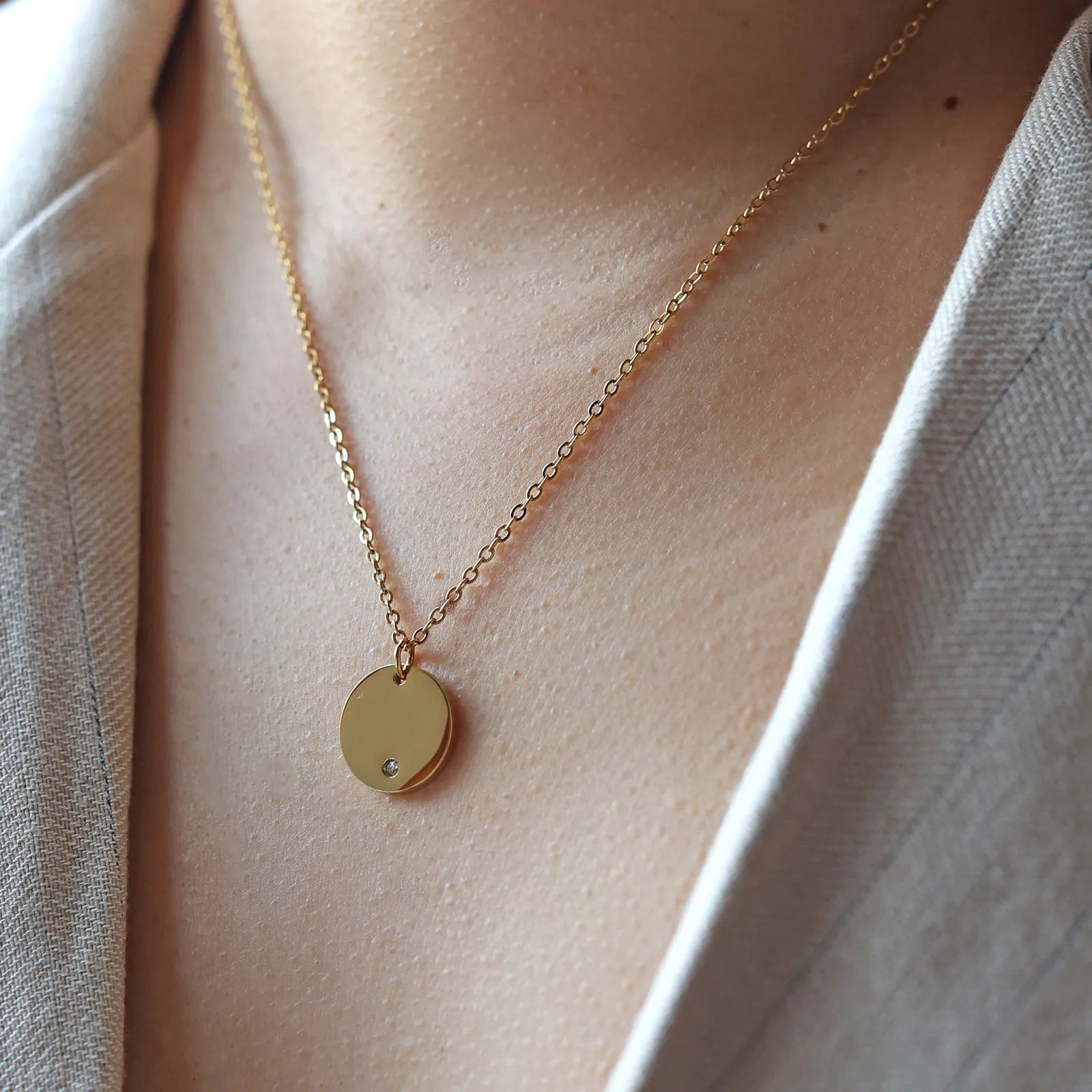 Collier personnalisable "Lumineuse", orné d'une médaille ronde brillante en acier doré, porté autour du cou.