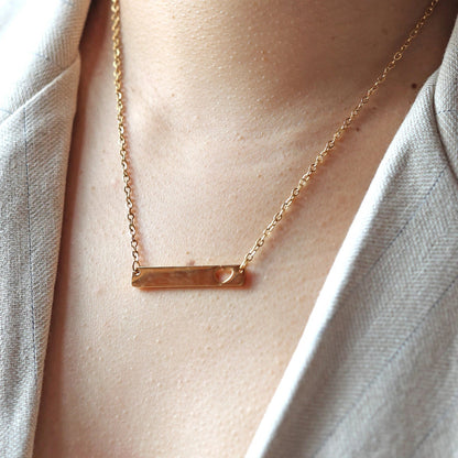 Collier plaque personnalisable en acier doré avec cœur découpé , porté sur un mannequin, photo en gros plan.