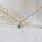 Collier "Mon identité" en acier doré, avec signe Capricorne et pierre bleue turquoise, délicatement suspendu sur une chaîne fine.
