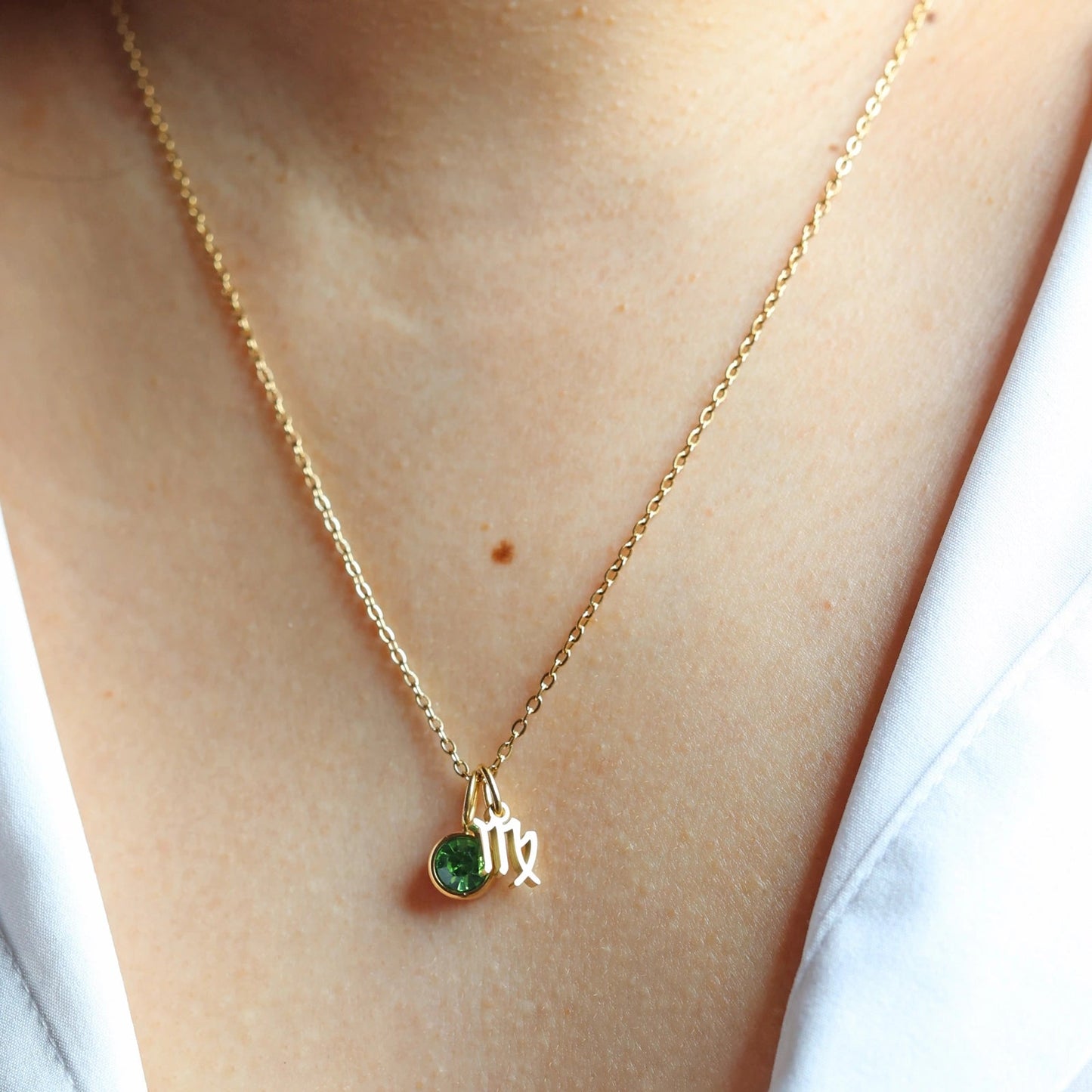 Collier "Mon identité" en acier doré, avec signe du zodiaque et pierre verte, porté autour du cou.