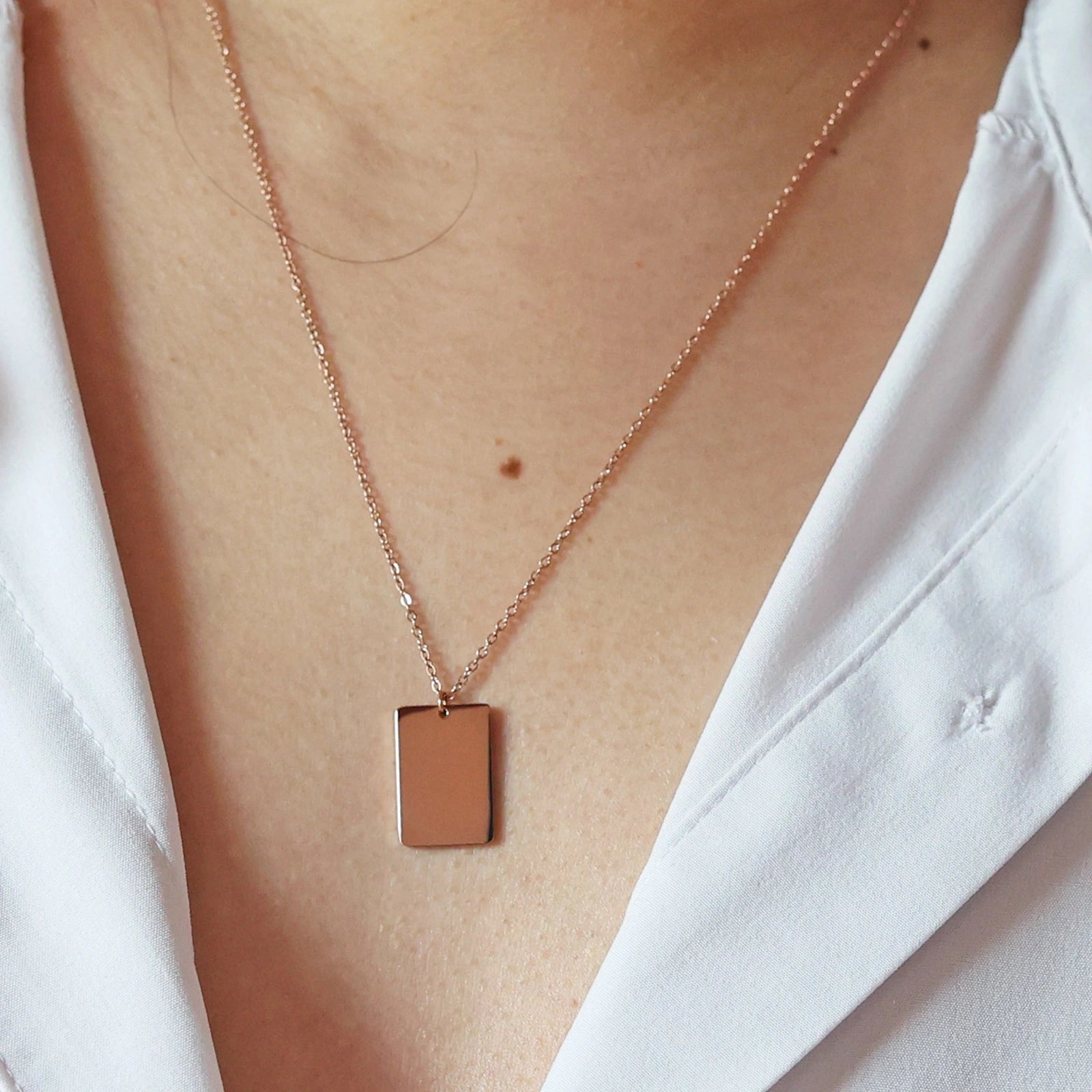 Collier "Je me souviens, en acier rosé, avec médaille rectangulaire à graver, porté autour du cou.