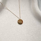 Zoom sur le collier "Reflet" avec médaille ronde personnalisé "Gabin" en acier inoxydable rosé.