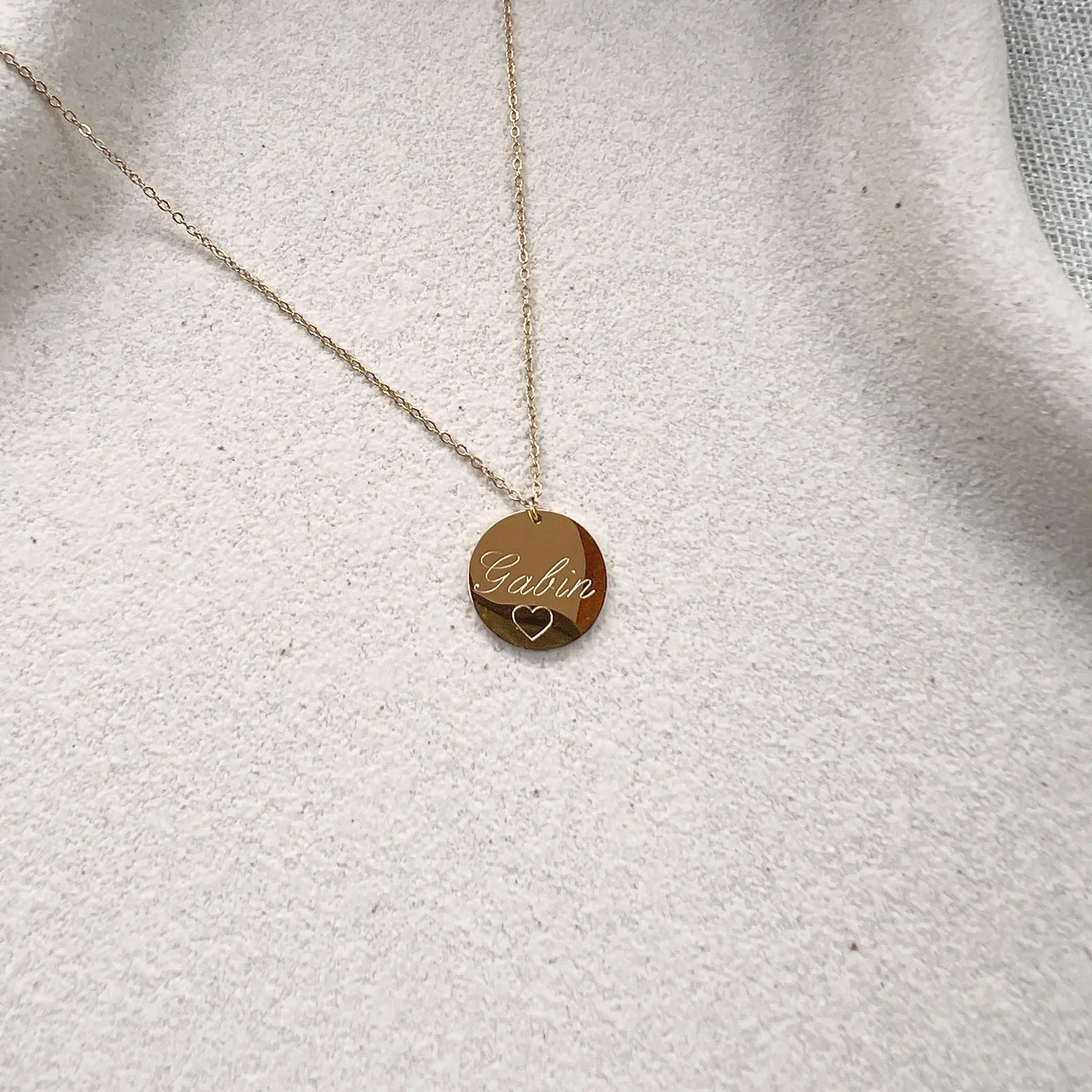 Zoom sur le collier "Reflet" avec médaille ronde personnalisé "Gabin" en acier inoxydable rosé.