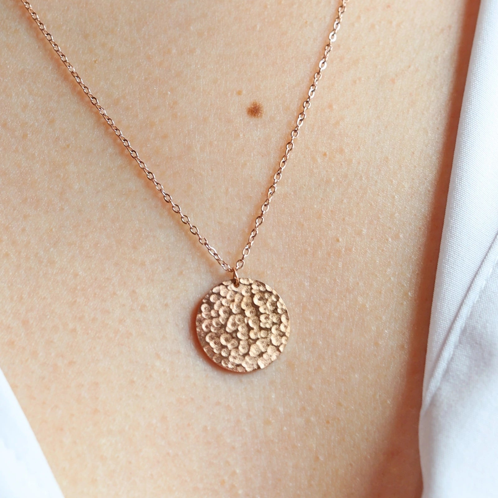 Collier Renaissance or rose, médaille ronde martelée à graver, porté autour du cou. 