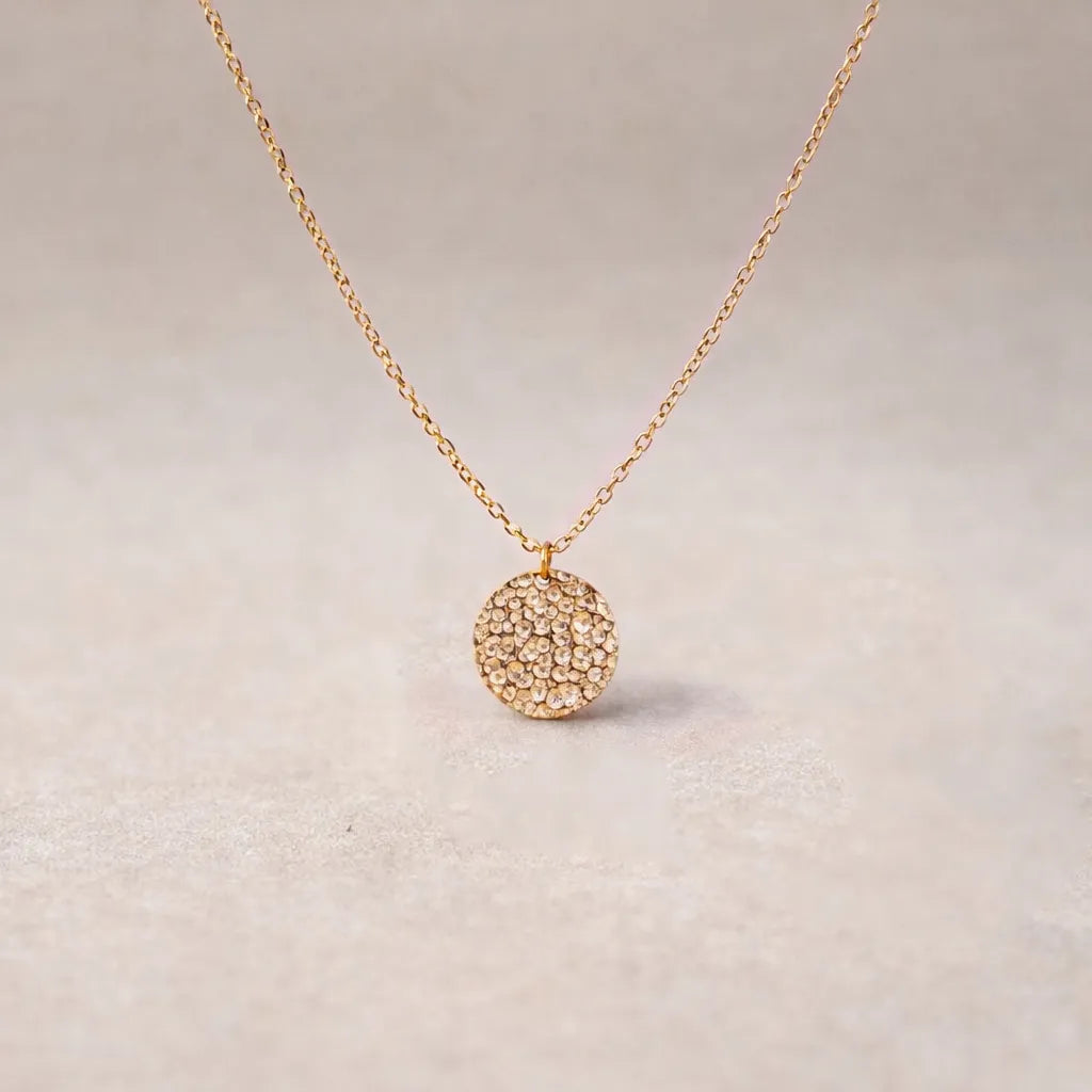 Collier Renaissance or rose, médaille ronde martelée à graver vue de face, posé sur fond beige texturé.