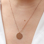 Collier "Reflet" avec médaille ronde personnalisé en acier inoxydable rosé, porté autour du cou.