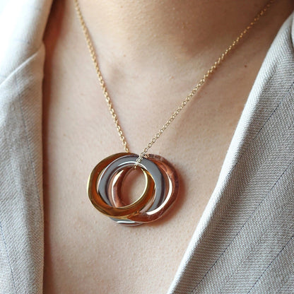 Collier "Je deviens" en acier doré, avec trois cercles entrelacés personnalisables, porté autour du cou.