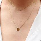 Double collier "Je me choisis" composé d'une perle et d'un médaillon en acier doré, porté autour du cou. 
