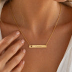 Collier personnalisable cœur doré, gravé au nom de Charlotte, portée sur une femme en chemise blanche– Douceur Visée Bijoux