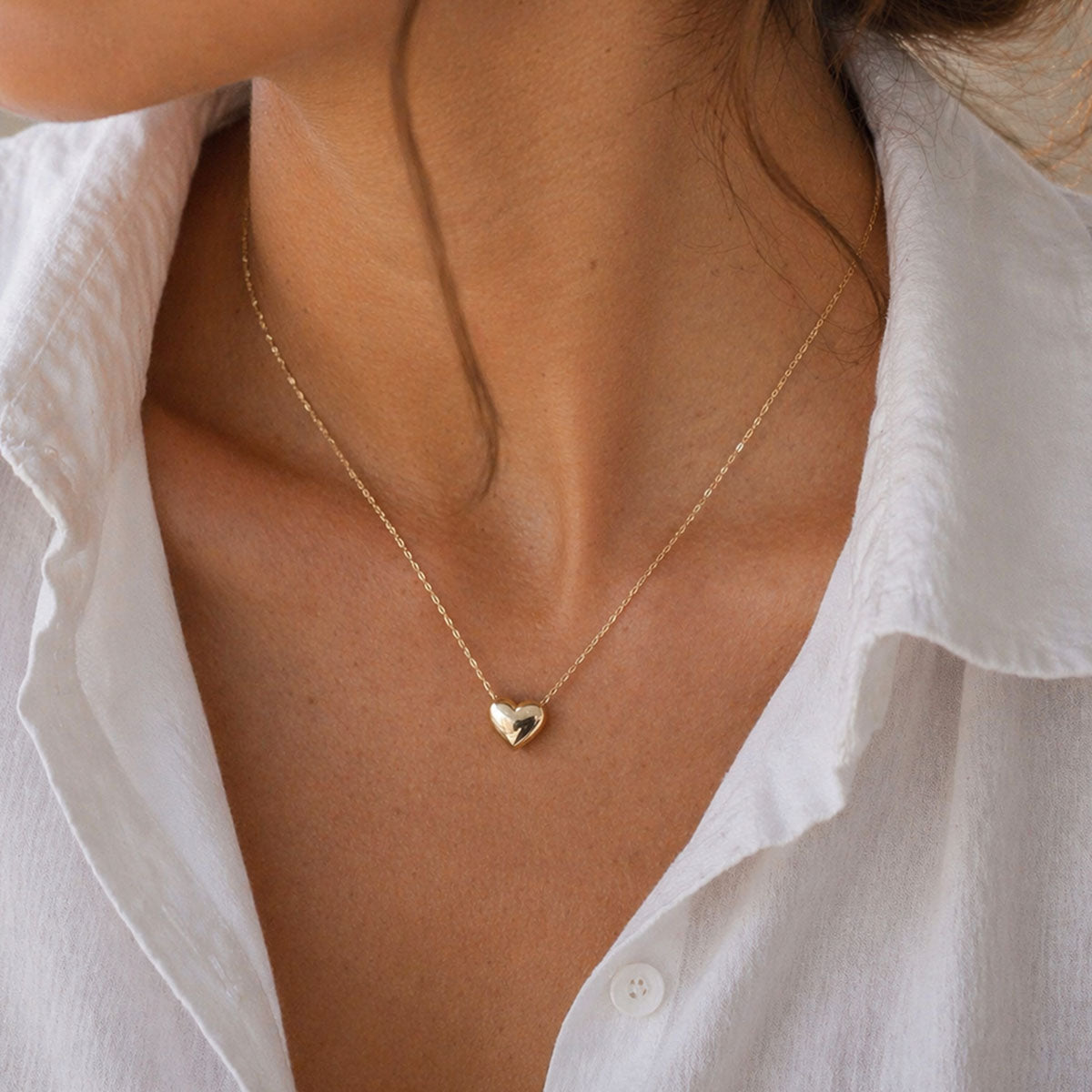 Collier Authentique avec pendentif cœur minimaliste en acier inoxydable doré, porté autour du cou.
