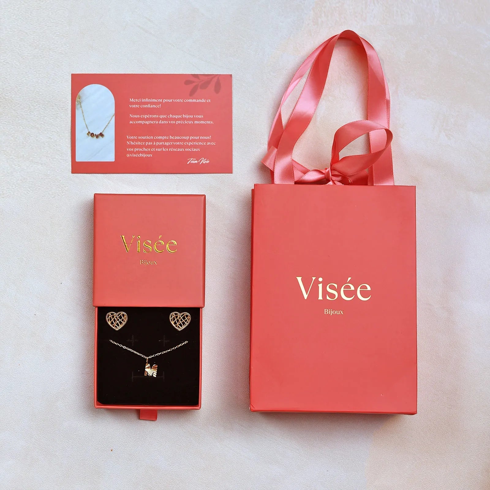 Coffret Évidence prêt à offrir comprenant: – Collier initiale & boucles cœur tressé Visée Bijoux , un coffret cadeau, un sachet cadeau et une carte de remerciement.