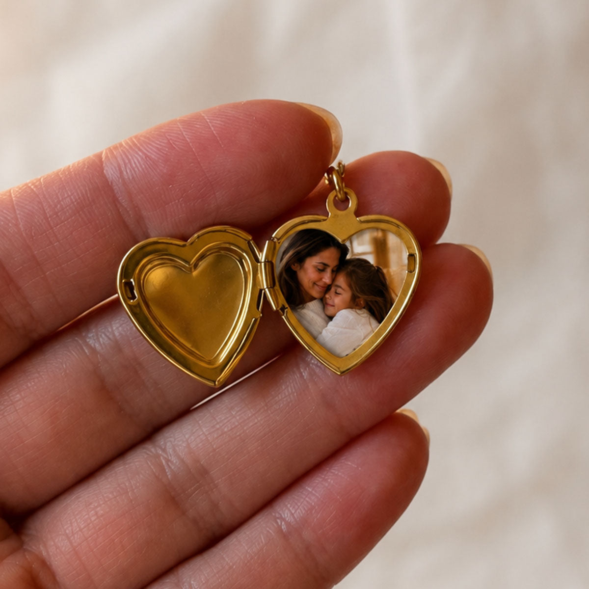 Zoom sur le collier Précieux, médaillon cœur en acier doré avec photo d'une maman et de sa fille, à personnaliser avec gravure sur le devant du cœur, ouvert dans la main.