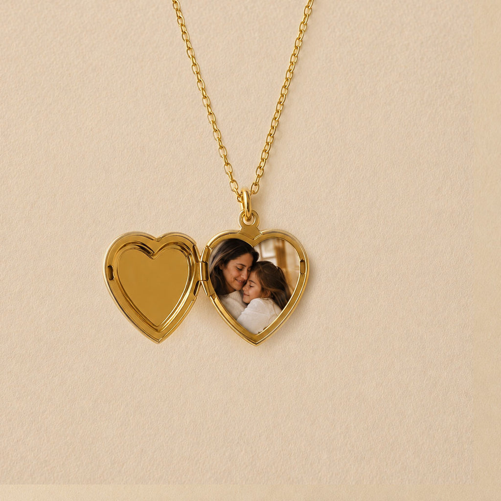 Zoom sur le collier Précieux, médaillon cœur en acier doré avec gravure et  photo d'une mère et de son enfant, souvenir à personnaliser, posé sur un fond beige texturé.
