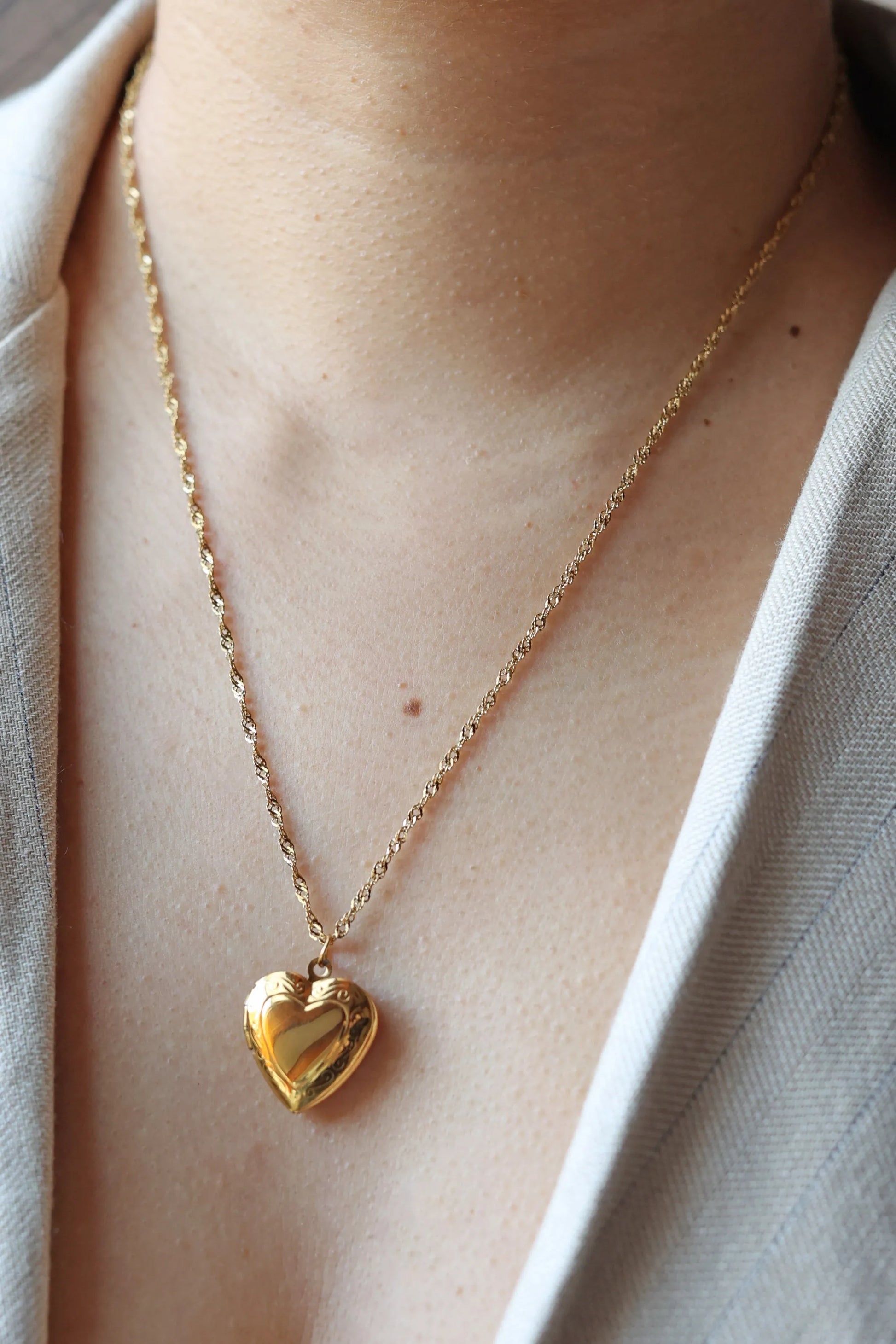 Collier médaillon cœur MANON en acier inoxydable doré, personnalisable pour y insérer des photos souvenirs.