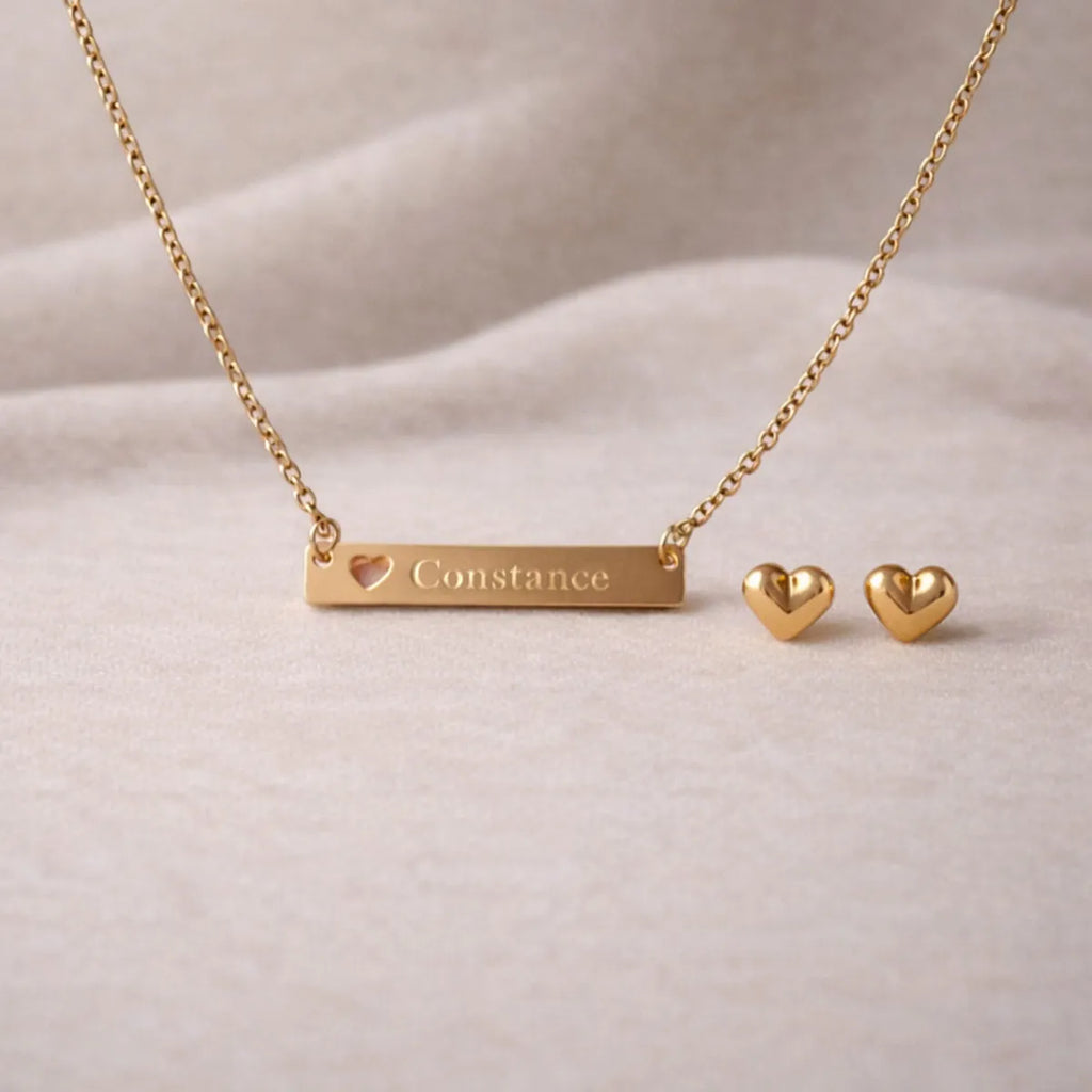 Collier personnalisé doré Douceur et les boucles d'oreille Doux en acier inoxydable doré, posé sur un fond beige texturé.