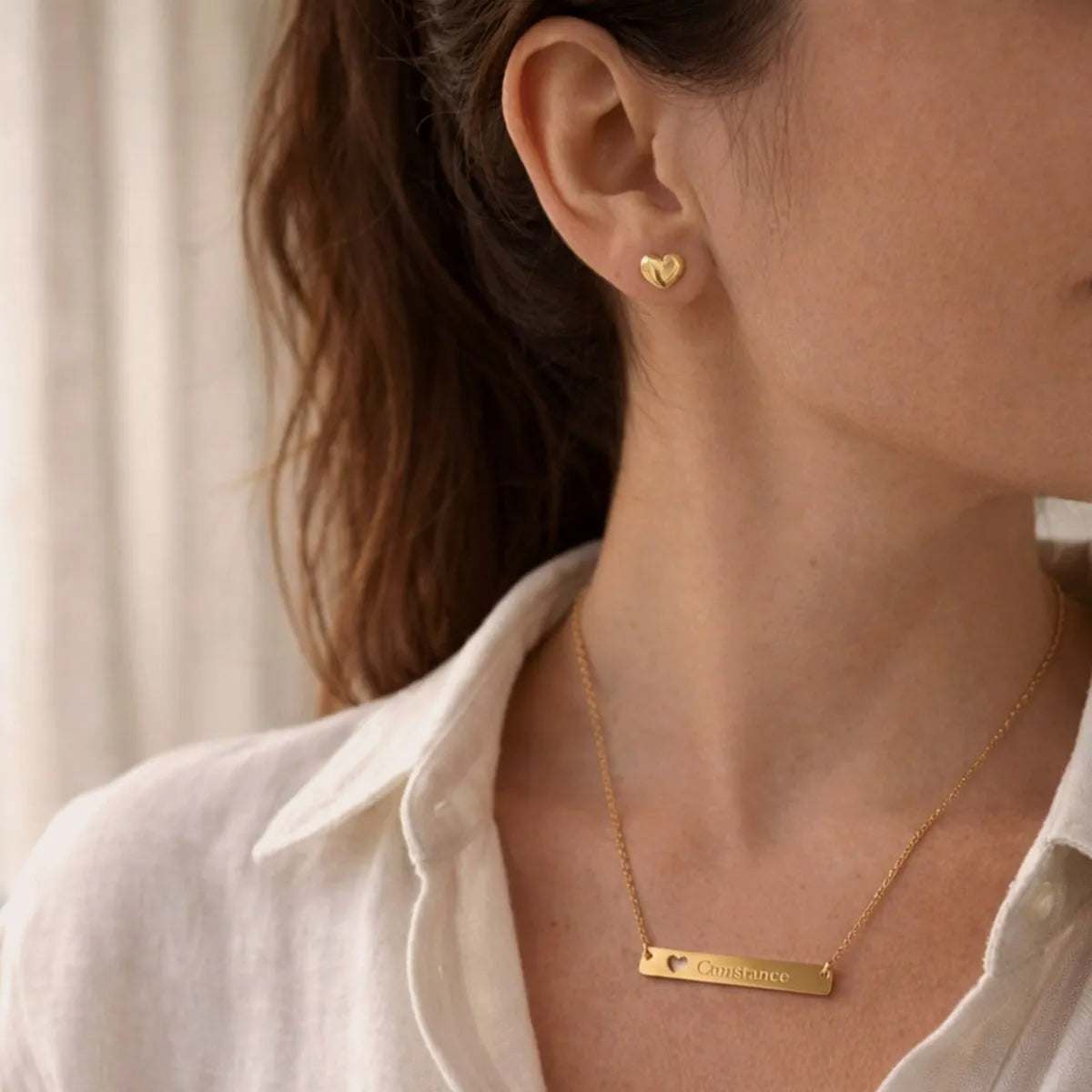 Collier personnalisé doré Douceur et les boucles d'oreille Doux en acier inoxydable doré, porté en parure sur une belle mannequin. 