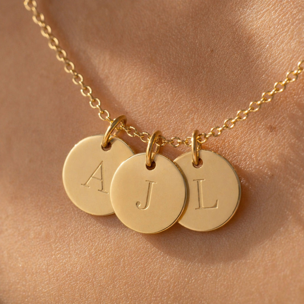 Collier Inspiration en acier doré, 3 médaillons personnalisables gravés en macro avec les initiales A j et L, porté sur peau 