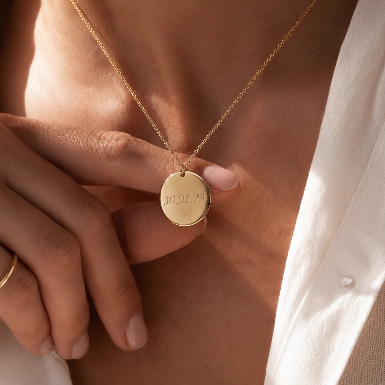 Collier médaille ronde personnalisable au recto et verso avec prénom, initiales et dates en dorée, portée sur une mannequin— Reflet Visée Bijoux