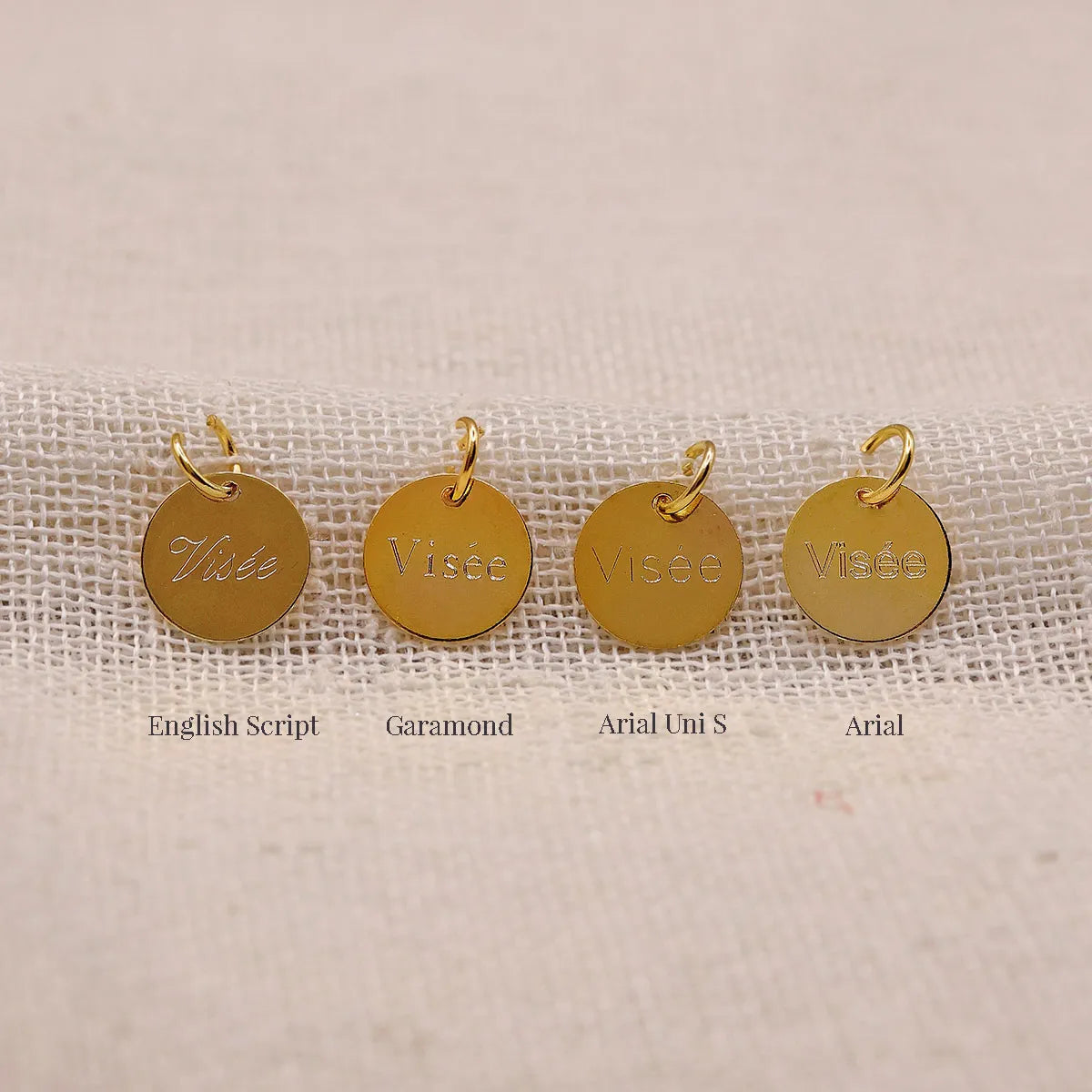 Comparatif des gravures Visée sur médaillons dorés: English Script, Garamond, Arial Uni S et Arial, sur fond tissu écru