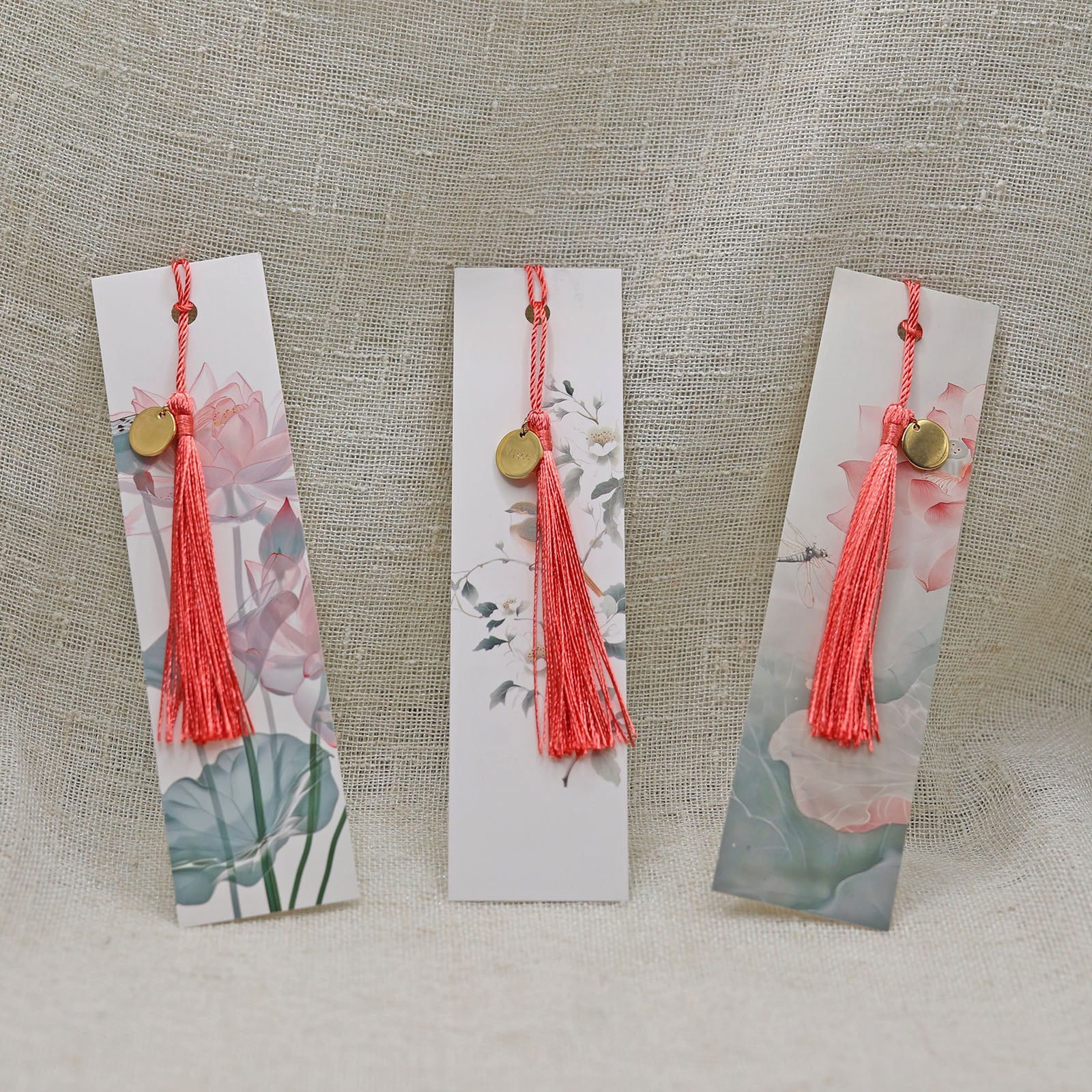 Trois marque-page Visée Bijoux à motifs floraux avec médaillon et pompon.