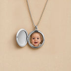 Médaillon rond argenté ouvert, photo d'un bébé insérée à l'intérieur