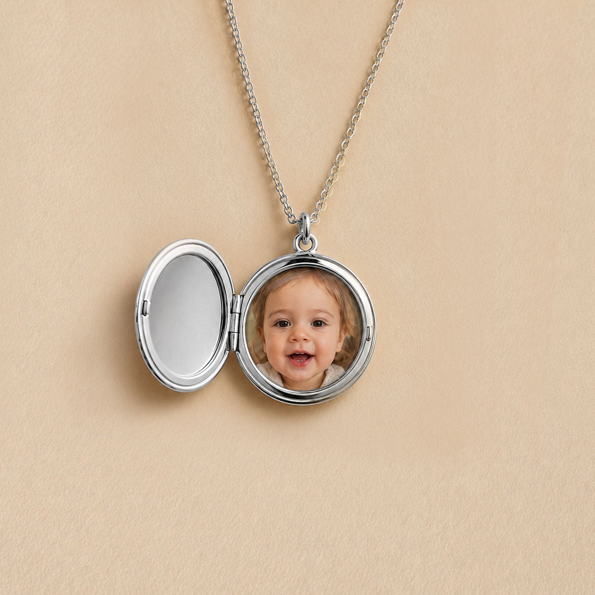 Médaillon rond argenté ouvert, photo d'un bébé insérée à l'intérieur