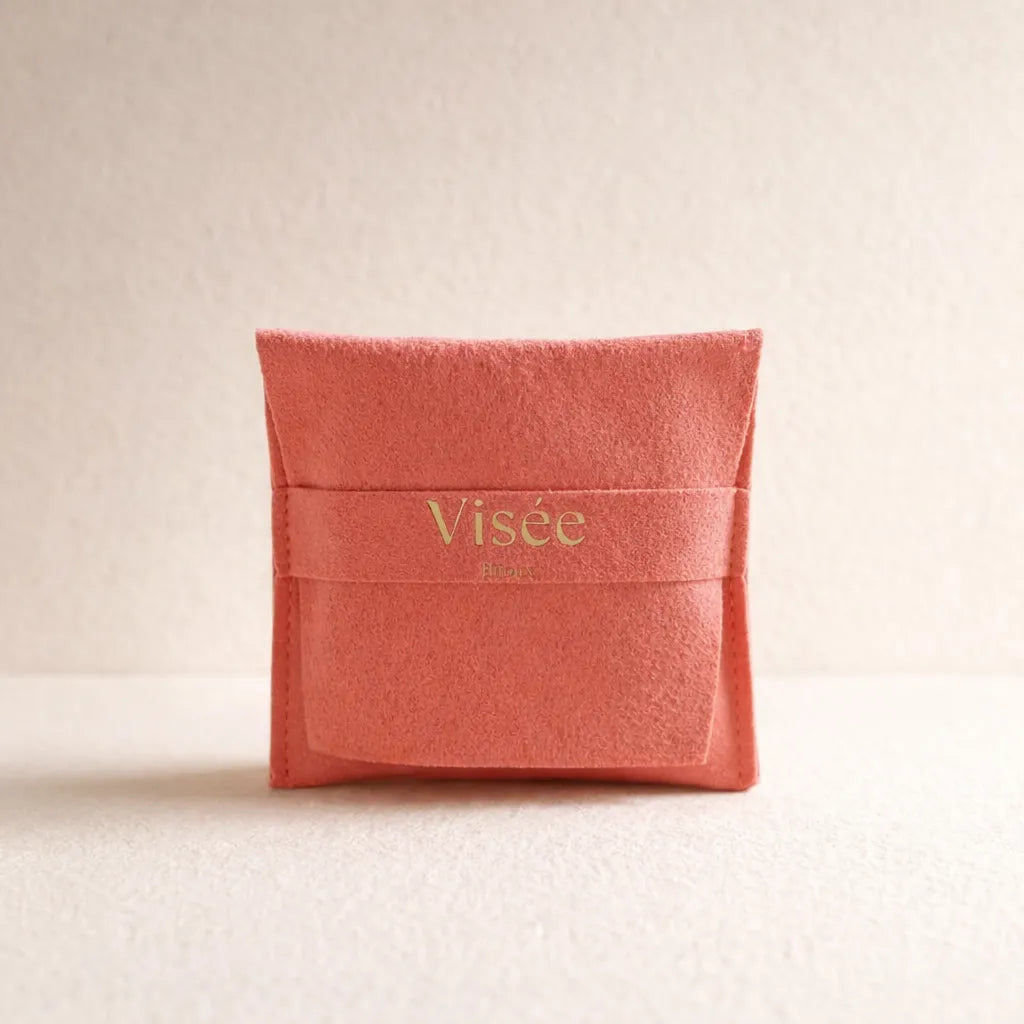 Pochon cadeau en suédine corail Visée Bijoux, posé sur un fond beige.