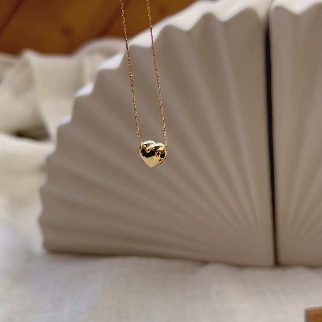 Vidéo du collier Authentique avec pendentif cœur personnalisable, en acier inoxydable doré, en vue d'ensemble sur un fond beige texturé.