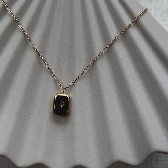 Vidéo du collier "Ma voie" avec pendentif rectangulaire personnalisable en acier doré, sur fond beige texturé.