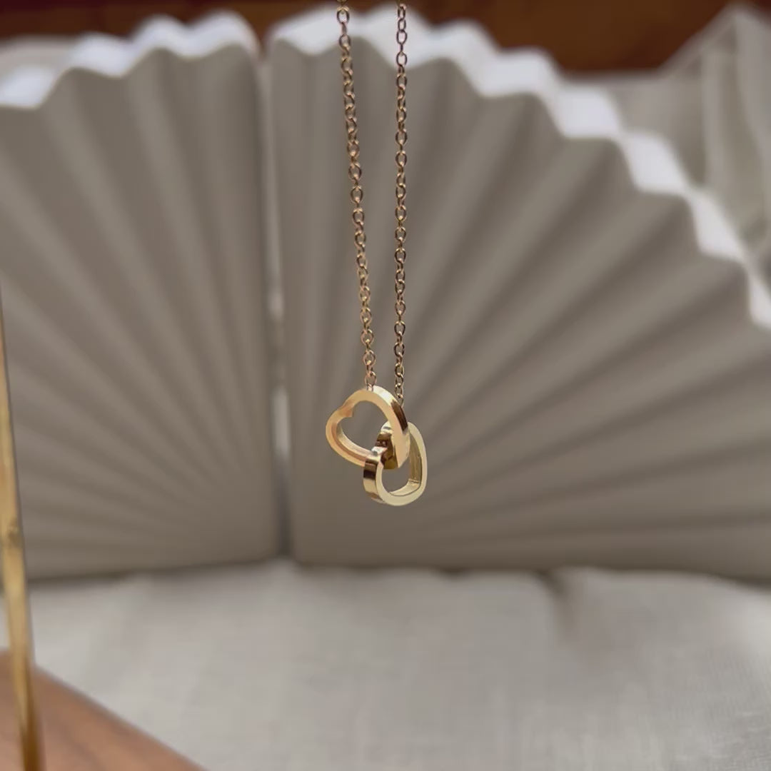 Vidéo du collier Toi et moi en acier inoxydable doré, deux coeurs entrelacés.