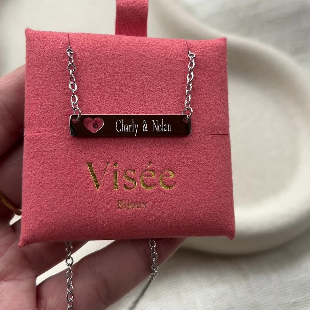 Vidéo du collier "Touchante" avec plaque personnalisable en acier argenté avec cœur découpé, gravé aux noms de Charly et Nolan