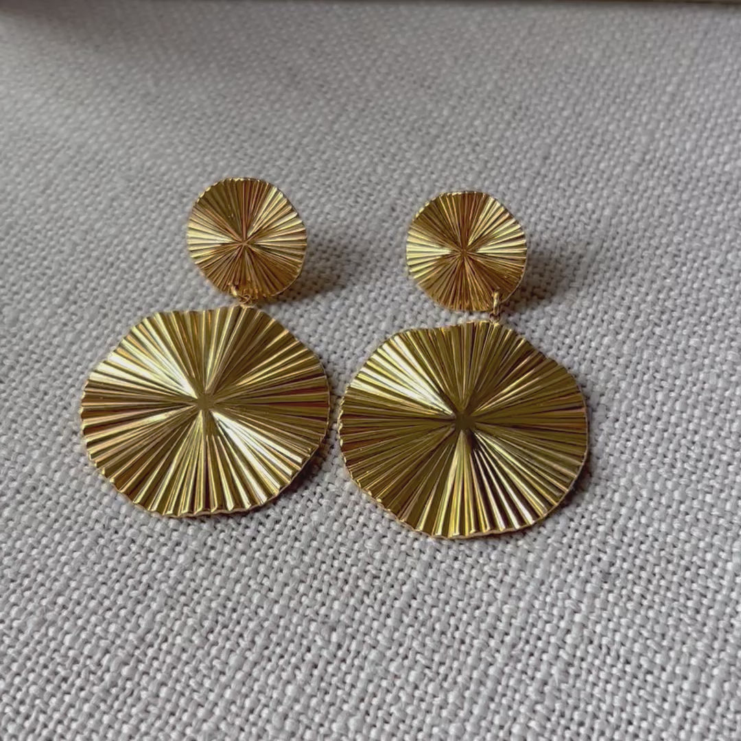 Vidéo des boucles d'oreilles Vivante pendantes au design solaire strié en acier inoxydable doré.