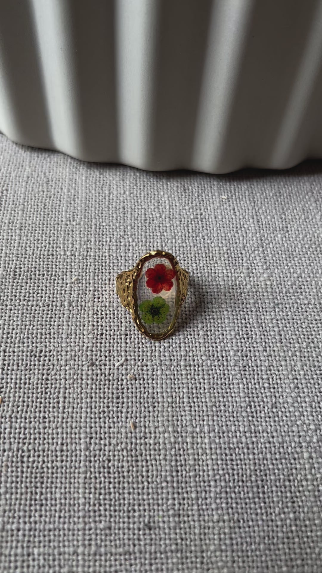 Vidéo de la bague ajustable Mon rythme, en acier inoxydable doré, ornée de deux fleurs séchées rouge et verte.