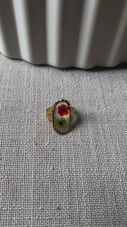 Vidéo de la bague ajustable Mon rythme, en acier inoxydable doré, ornée de deux fleurs séchées rouge et verte.