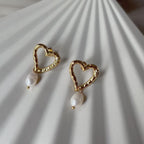 Vidéo des boucles d'oreilles en forme de coeurs Loyale en acier inoxydable doré, ornée de deux perles blanches