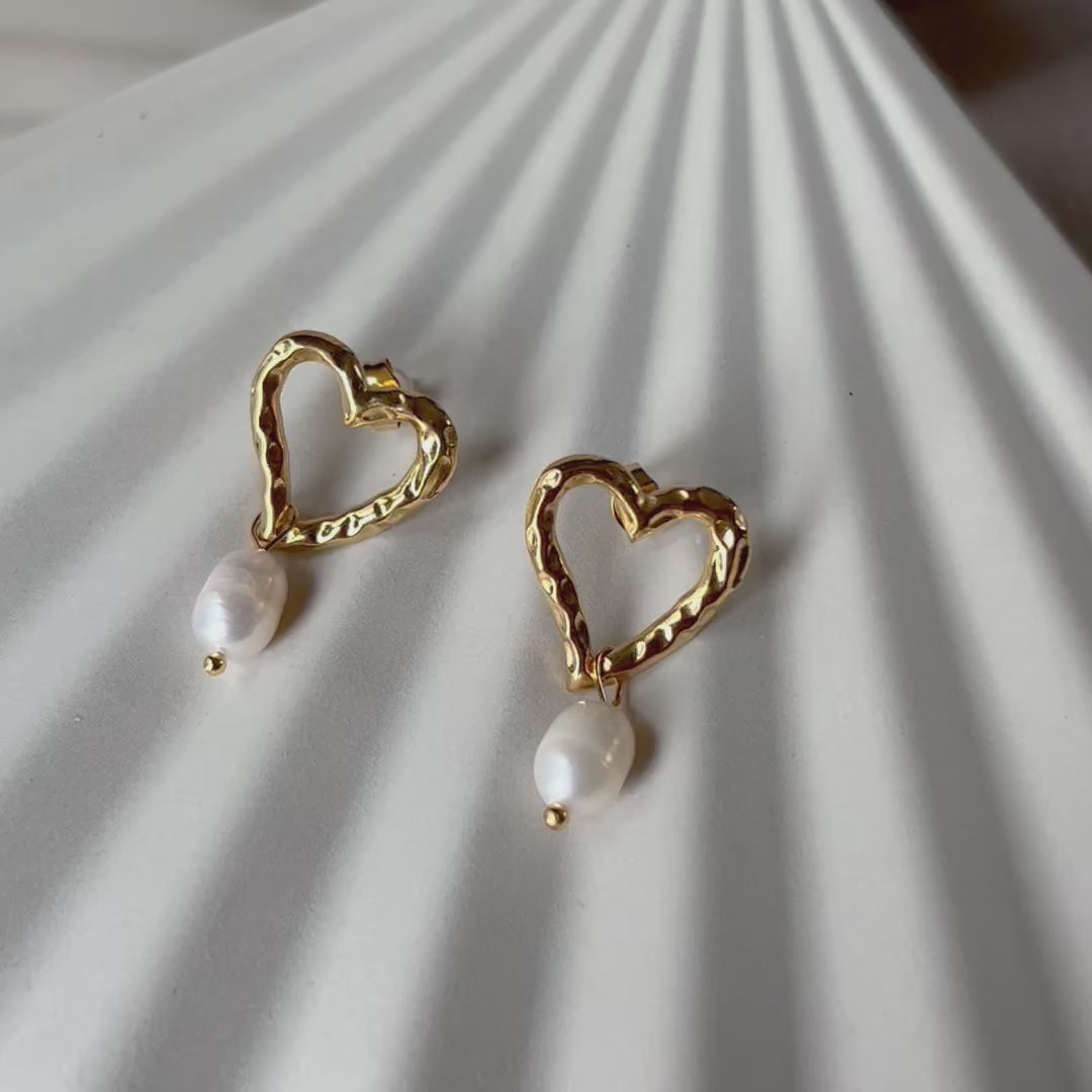 Vidéo des boucles d'oreilles en forme de coeurs Loyale en acier inoxydable doré, ornée de deux perles blanches