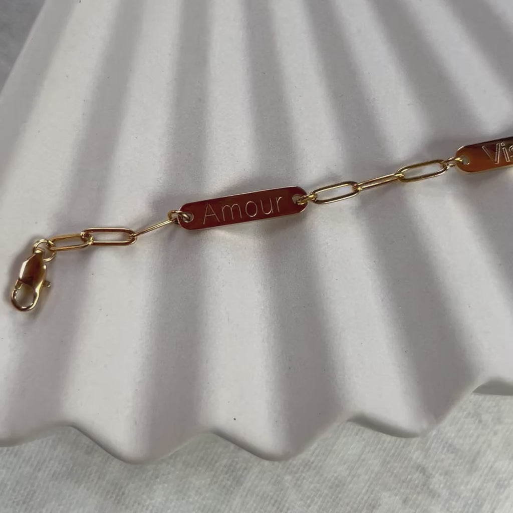 Vidéo du bracelet "Expression" en acier inoxydable doré, à personnaliser avec  plaques personnalisables, présenté sur un fond beige texturé.