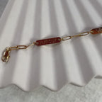 Vidéo du bracelet "Expression" en acier inoxydable doré, à personnaliser avec  plaques personnalisables, présenté sur un fond beige texturé.