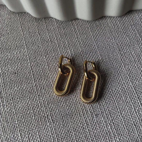 Boucles d'oreilles "J'existe" en acier doré, au design modulable.