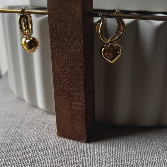 Vidéo des boucles d'oreilles "Amour suspendu" de Visée, avec pendentifs coeurs en acier doré.