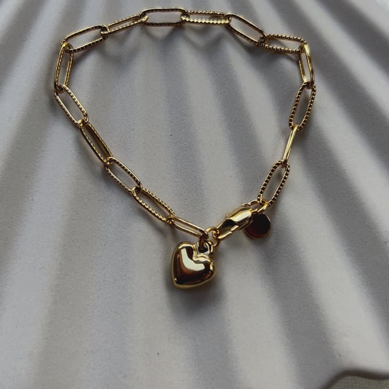 Vidéo du bracelet Valeur acier inoxydable doré, avec breloque cœur personnalisable, posé sur un fond beige texturé.