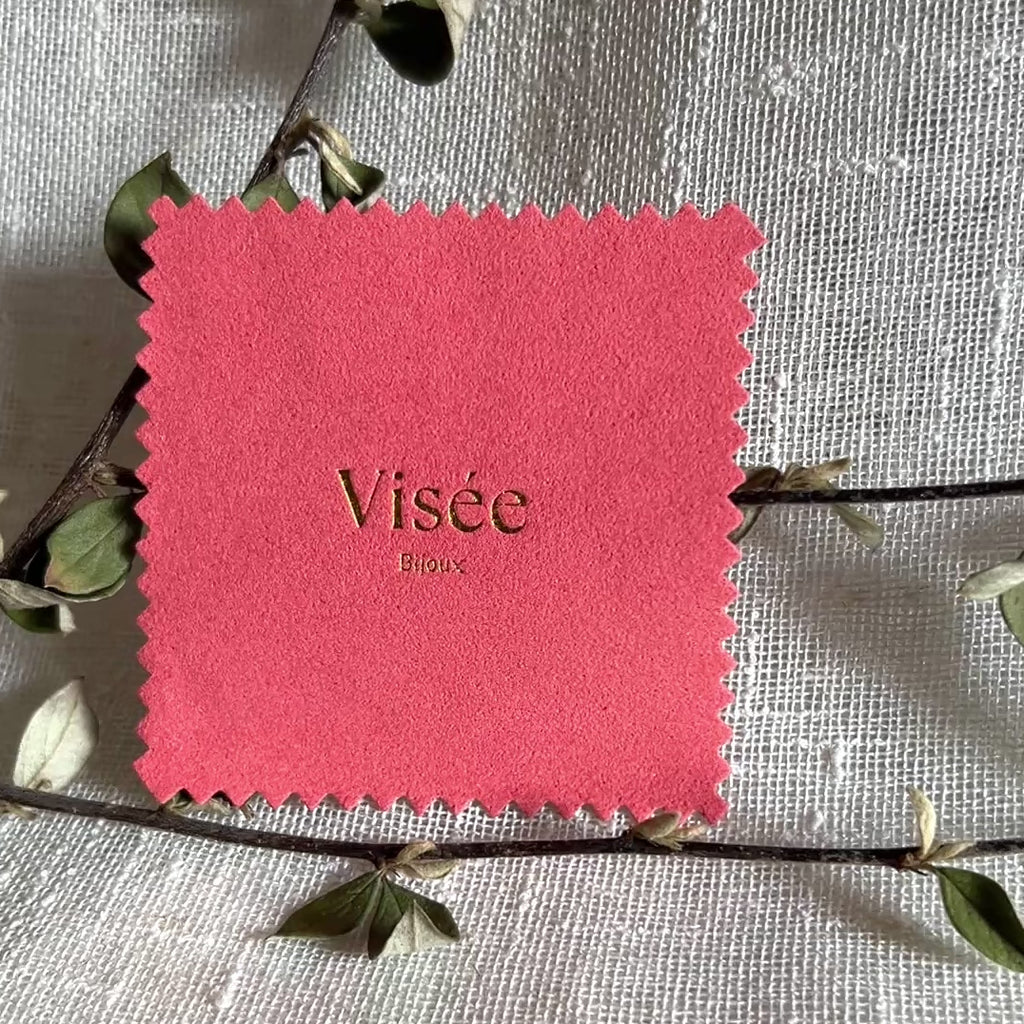 Vidéo de la chamoisine Visée en suédine corail, pour l'entretien délicat des bijoux, photographiée sur un fond beige et posé sur une branche