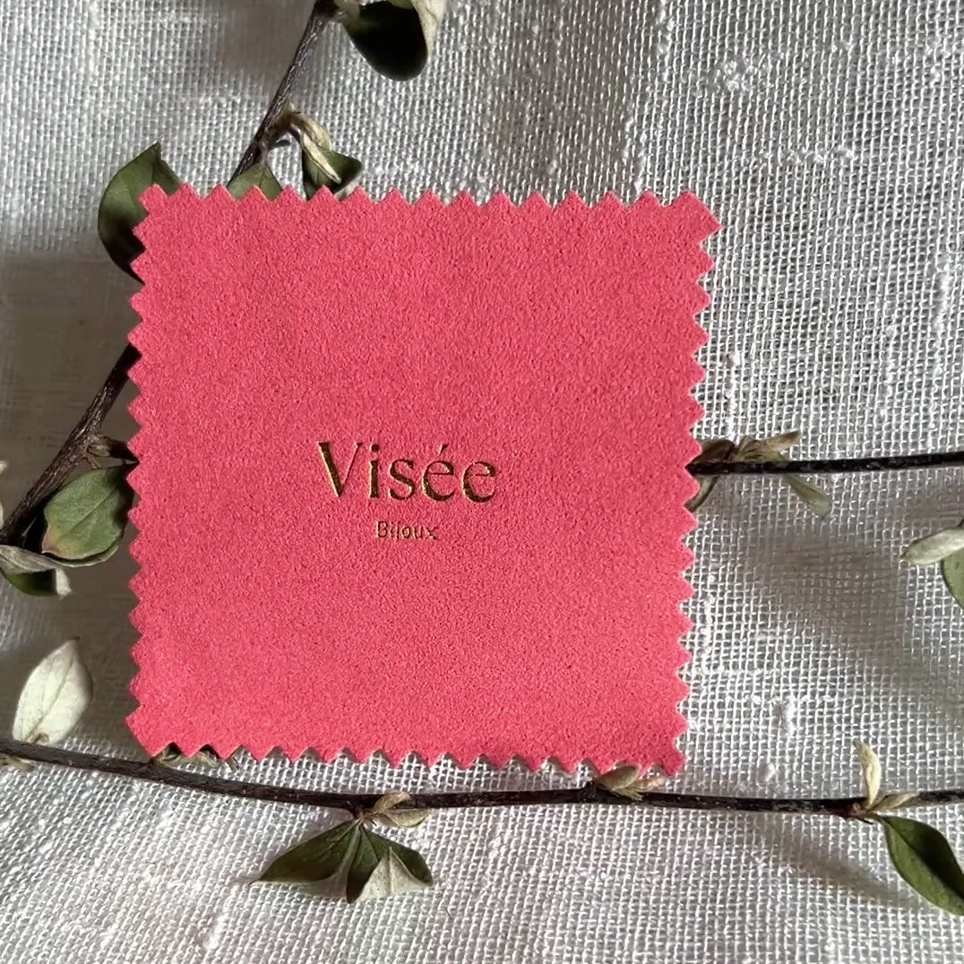 Vidéo de la chamoisine Visée en suédine corail, pour l'entretien délicat des bijoux, photographiée sur un fond beige et posé sur une branche