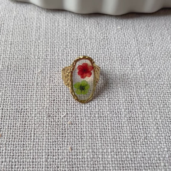 Vidéo de la bague ajustable Mon rythme, en acier inoxydable doré, ornée de deux fleurs séchées rouge et verte.