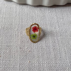 Vidéo de la bague ajustable Mon rythme, en acier inoxydable doré, ornée de deux fleurs séchées rouge et verte.