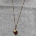 Vidéo du collier "Entre nous", médaillon cœur en acier doré avec photo souvenir à personnaliser, posé sur un fond beige texturé.