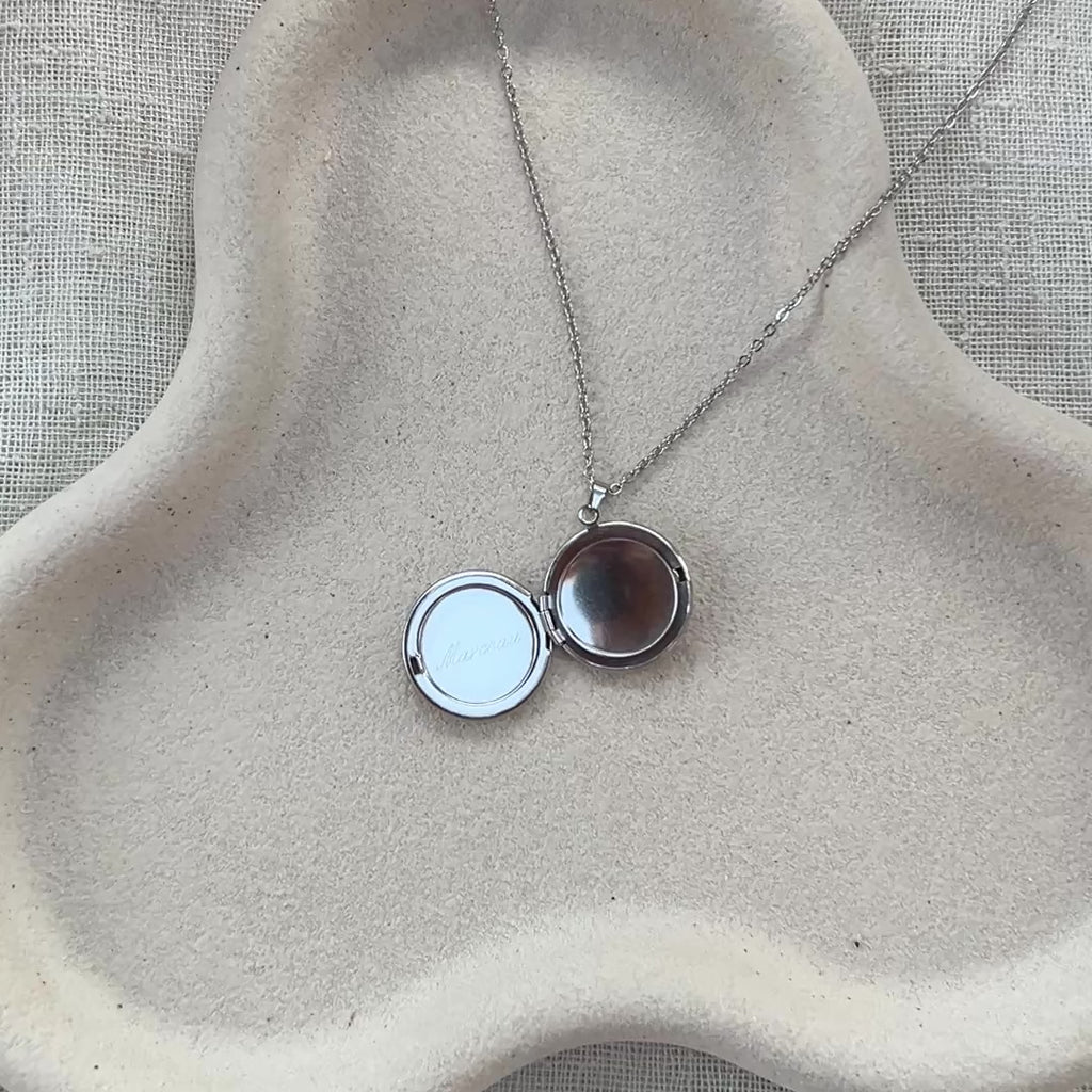 Vidéo du collier "Ce jour là" avec médaillon rond personnalisable en acier argenté, présenté sur un fond beige texturé, gravé du prénom Marceau. 